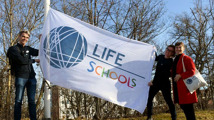 Magnus Köpman, LHU-koordinator och lärare, hissar LIFE School-flaggan tillsammans med Therese Rosenblad och Sara Jansson från LIFE Academy. 