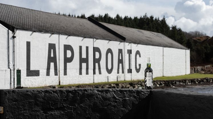 Laphroaig36YearOldWallCollection_BottleInFrontOfDistillery.jpg