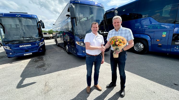 BLOMSTER: Scanias busselger Tore Aasgaard kunne overrekke en blomst sammen med de tre nye bussene til adm.dir. i JVB Helge Kvame. 