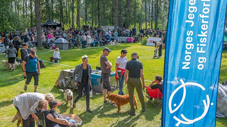 En folkemengde samlet rundt en utstillingsring på hundeutstilling. Et banner med Norges jeger- og fiskerforbund i forgrunnen.