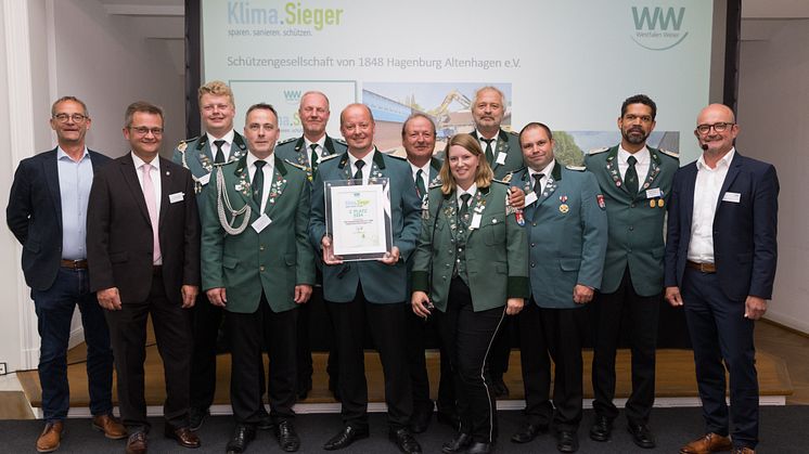 Jury-Mitglieder Heinz-Jörg Heinemann (links) und Andreas Speith (rechts) gratulieren zusammen mit dem Bürgermeister der Samtgemeinde Sachsenhagen Jörn Wedemeier (2. v. l.) der Schützengesellschaft. 