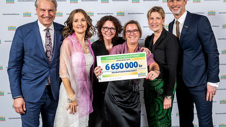 Reumatikerförbundets ordförande Lotta Håkansson tar emot en check från Svenska PostkodLotteriet. 