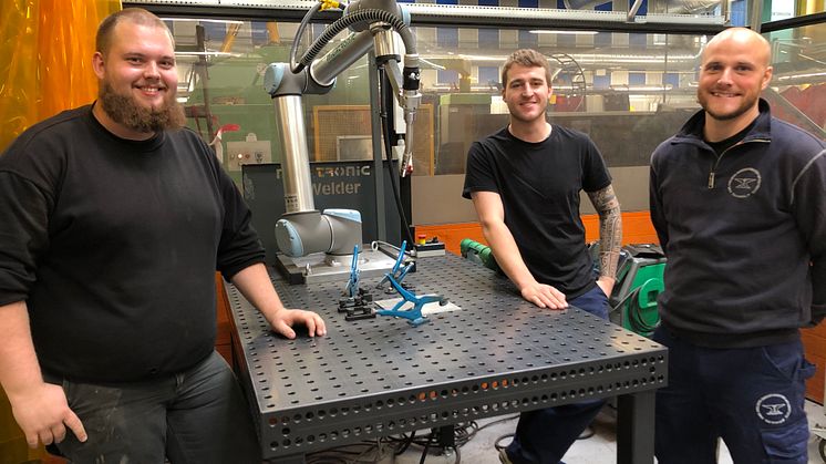 Smedelærlingene Mikkel, Alexander og Nicky med den kollaborative robot, CoWelder