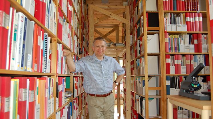 På bilden står Sven Werner i sitt omfattande forskningsarkiv. Han är professor emeritus i energiteknik och knuten till Högskolan i Halmstad.