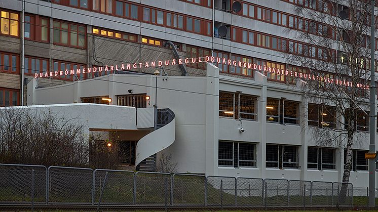 Bokstäverna i Alexandra Stratimirovics ljusgestaltning ligger som en ljuskrona över garagebyggnaden. Vid en närmare titt bildar bokstäverna ord och meningar.