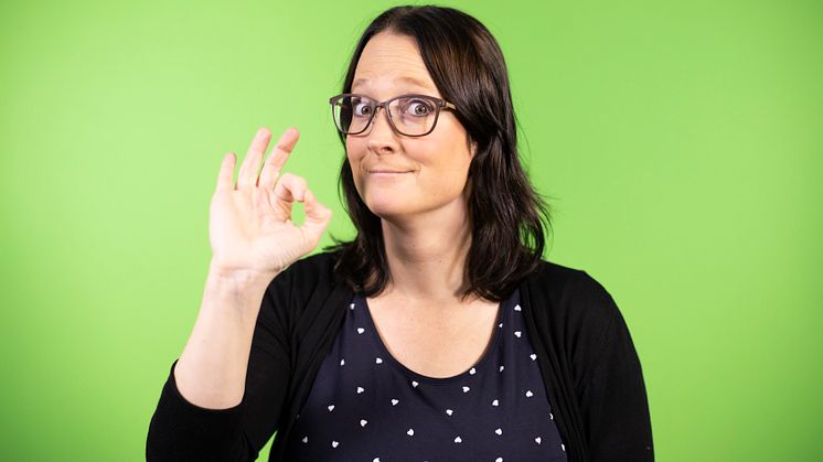Maria Norberg, konsult på Teckenbro, medverkar i seminariet "Hög tid för teckenspråkiga böcker!" på Bokmässan 2021. På fotot gör hon tecknet perfekt mot en grön bakgrund. Foto: Mikael Sundberg/MTM.