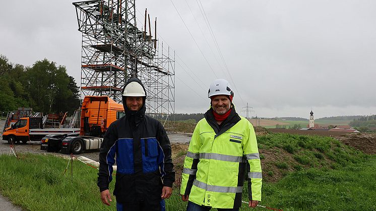 Bauleiter Claus Pfaffenberger (r.) und Baukontrolleur Norbert Radlmaier vor dem Übergangsmast. Hier wird das neue Hochspannungskabel vom Umspannwerk Tann mit der bestehenden Freileitung verbunden.