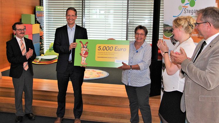Den Kinderbibliothekspreis überreicht Ingo Schroers vom Bayernwerk an Bibliotheksleiterin Cornelia Kempgen (mi.). Pfarrer Walter Ries (li.), Dr. Claudia Pecher vom St. Michaelsbund (2. v.r.) und Bürgermeister Thilo Wagner gratulieren.