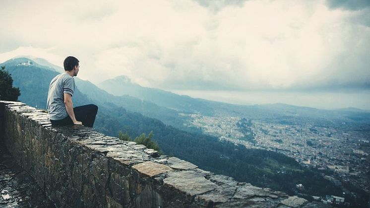 Man sitting on rock wall and overlooking city