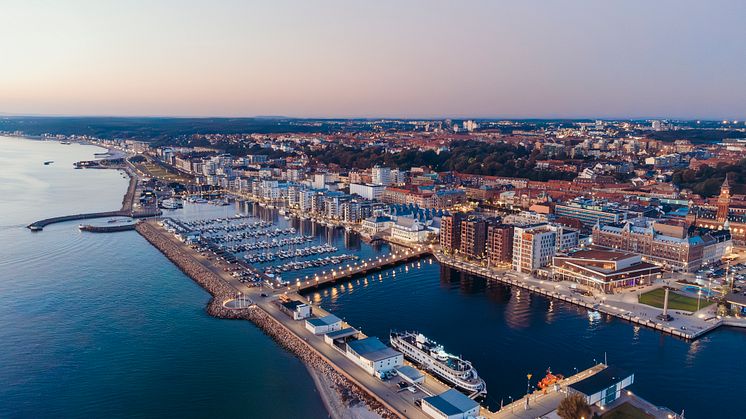Drönarbild över norra hamnen i Helsingborg. Det är lätt kvällsljus. Man ser båtarna i hamnen i förgrunden och längre bak stad