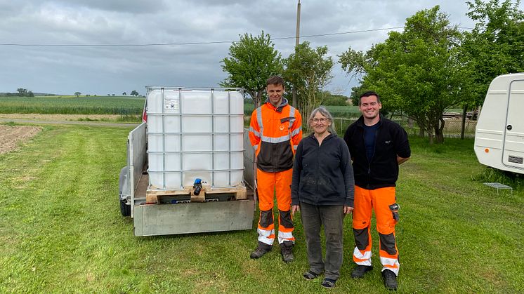 Ursula Rauwolf (mit Sebastian Pfaff, r., und Rico Huhn) von der Baumwege-Initiative Grimma freut sich über die Lieferung des ersten Behältnisses, in dem Regenwasser zum Gießen der Bäume aufgefangen werden soll.
