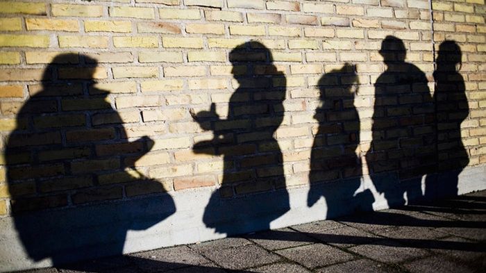 Alla som söker kulturstöd från Stockholms läns landsting måste intyga att de arbetar mot sexuella trakasserier. Foto: Maskot bildbyrå. Syntolkning: skuggor mot tegelvägg av människor i kö.