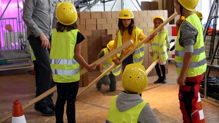 Kinder errichten zusammen einen Dachstuhl aus Holz