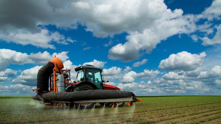 Tractor spraying soybean crops field at spring season, often using herbicides, which may leech through the soil into water sources below and possibly end up in human or animal drinking water.