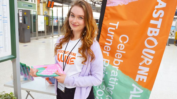 Phoebe Ociepka-Tearle helps to direct people arriving by train to the gallery, whilst enticing other members of public to visit the exhibition