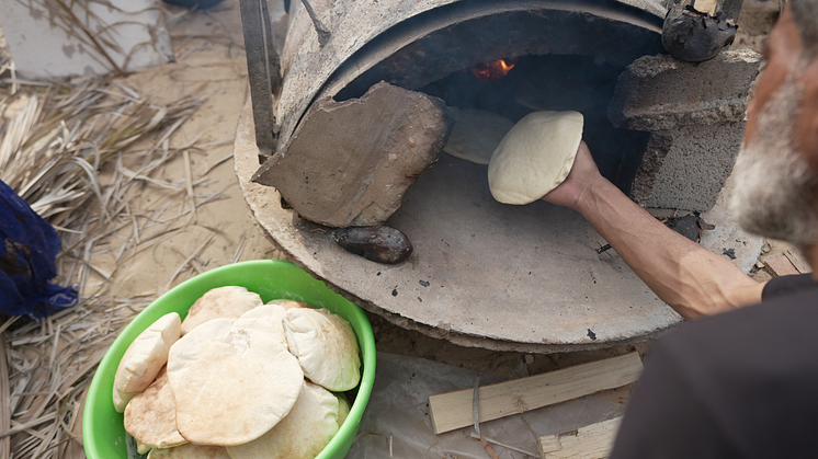 Mutaz använder ugnen de byggt av lera för att göra bröd. Foto: Alef Multimedia/Oxfam