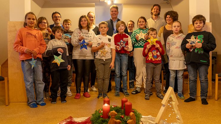 Abholung der Sterne bei der Paul-Moor-Tagesstätte der KJF Donau-Ries in Donauwörth: Kinder und Einrichtungsleiterin Vesna Milijic (mittlere Reihe rechts) präsentieren den LEW-Vertretern (hintere Reihe) ihre mit Wünschen versehenen Sterne.
