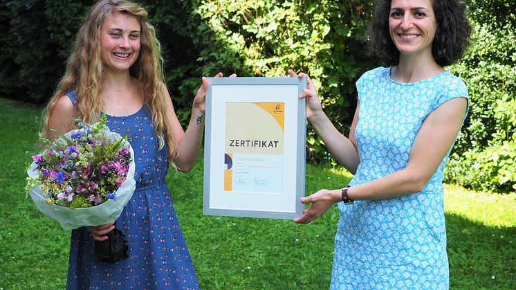 Christina Schuh (li.) erhält von Serap Meral (re.), Account Manager Clinics von Cochlear Deutschland, das Cochlear™ Graeme Clark Stipendium 2021