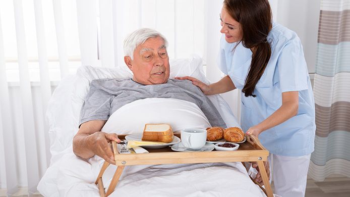 Patient får frukost serverad i sängen.