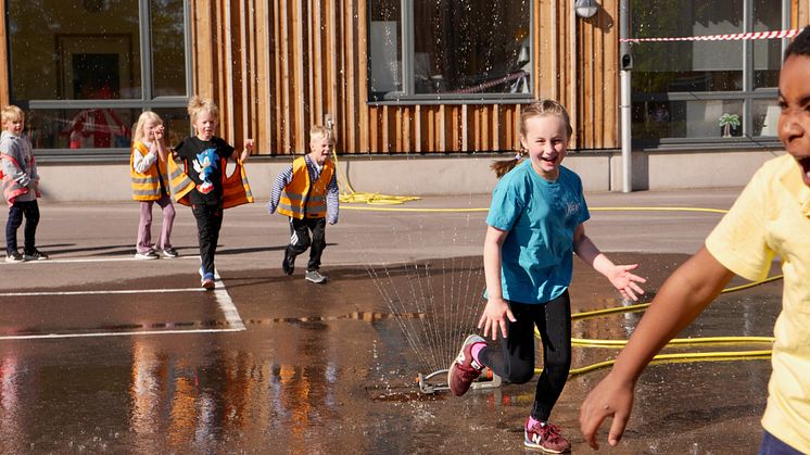 Glada barn på Västerstrandsskolan firar Generation Pep certifieringen ute på skolgården.