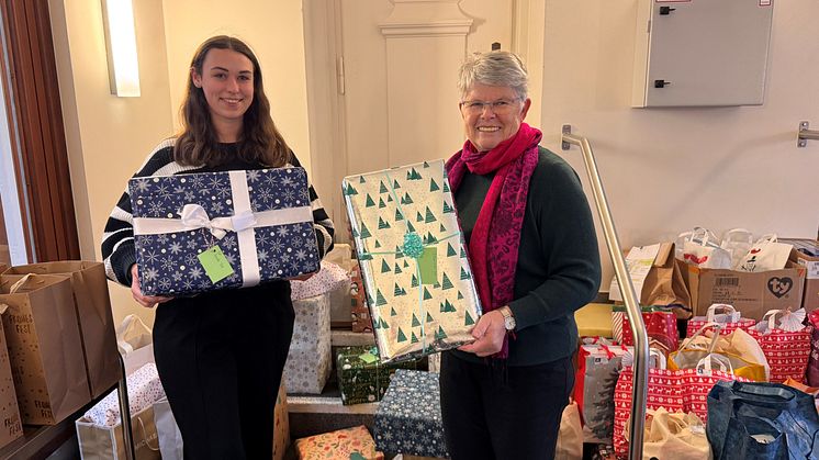 Katharina Hollendung, Trainee bei Deutsche Glasfaser, übergibt Geschenke an Hanne Watty von der Benrather Tüte.