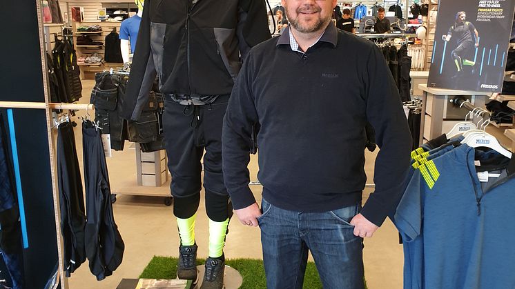 Chrsitian framför en skyltdocka med träningsinspirerade yrkeskläder, allt från strumpor, till leggings och shorts