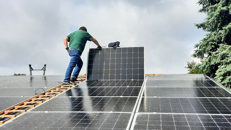 Zwei Menschen montieren eine Photovoltaik-Anlage auf dem Dach eines Hauses