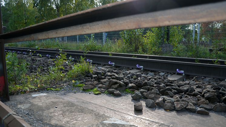 Konventionell järnväg möter järnvägsräls på solig betongplatta
