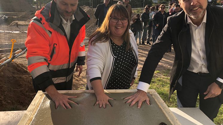 Peter Stråhlin, Åhlin och Ekeroth, Cecilia Burenby, kommunstyrelsens ordförande i Mjölby och Anders Stjärnberg, vd HSB Östergötland, skapar konstverk i betong under måndagens första spadtag för HSB brf Tallkotten