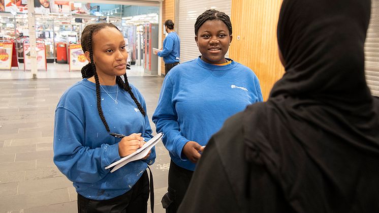 Ferieungdomarna Johanna Sentayehu, Velda Ewane och Dilan Salih (i bakgrunden) frågar Bergsjöbor om deras syn på valet och demokrati.