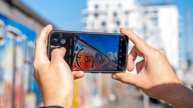 Berlin_Person_macht_ein_Handyfoto_von_Berliner_Mauer_mit_Eastside_Gallery