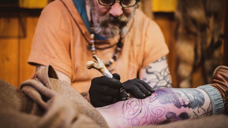 Tatuerare som tatuerar med historiska verktyg. Foto Zaneta