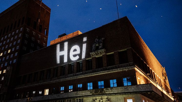 Denne uken har observante Oslofolk lagt merke til et lite ord, med stor betydning, på ulike bygg rundt omkring i byen. Ruter står bak projiseringen og vil de neste ukene fargelegge byen med enda flere hei-budskap.  Foto: Ruter/Jeton Kaçaniku