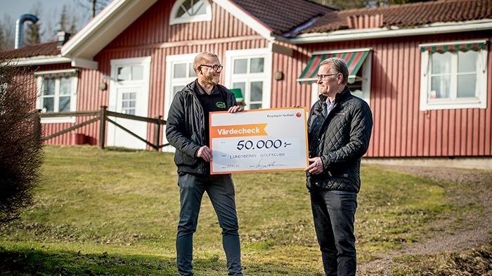 Joakim Kristoffersson, Lundsbergs Golfklubbs ordförande, tar emot check från Berry Andersson, kontorschef på bankens kontor i Storfors och Nora.