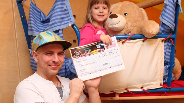 John Rahmlow mit seiner Tochter präsentieren stolz den Spendenscheck im Kinderhospiz Bärenherz