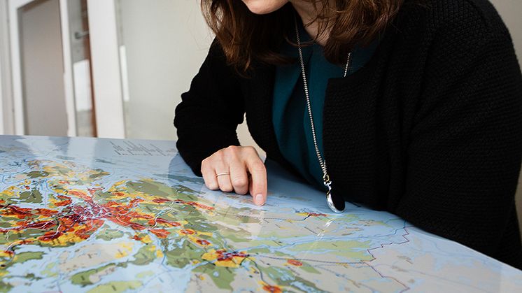 Foto: Anna Molander. Syntolkning: Kvinna som pekar på en stor världskarta.