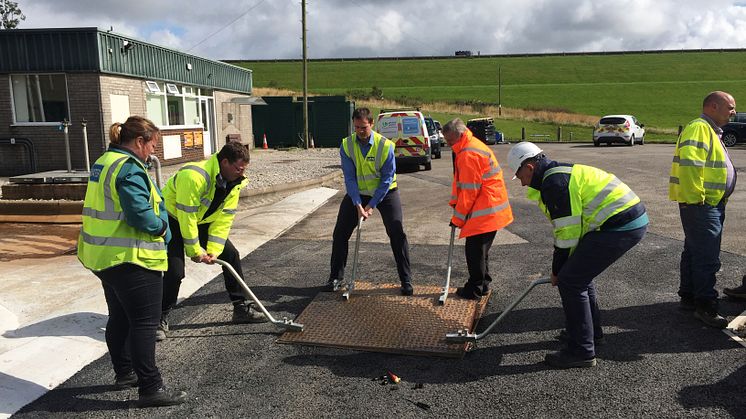 Heavy metal access cover requiring four people to remove and replace using unsafe lifting techniques
