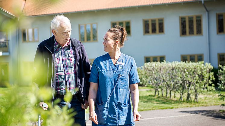 Anställd promenerar och pratar med omsorgstagare.