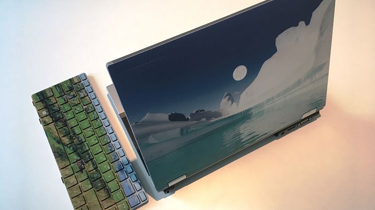 Dator med egen design. Tangentbord med böljande landskap från Skottland och datorlock med naturskönt motiv från Antarktis. 