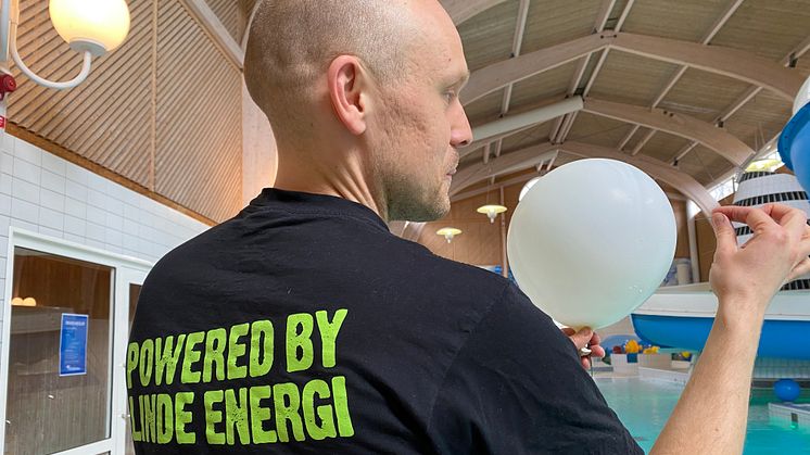 Fredrik Klingvall, kommunikationsansvarig på Linde energi, tar hjälp av nål för att spräcka hål på aprilskämtet. Foto: Linde energi