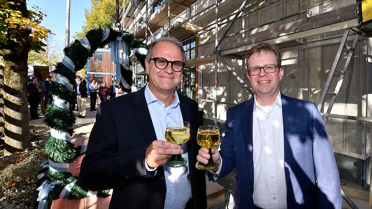 Dr. Bernd Hochberger (re.), Vorstandsmitglied der Stadtsparkasse München, stoßt zusammen mit dem Leiter des Immobilienmanagements, Michael Rubenbauer, auf das Richtfest des Neubaus in der Belgradstraße 162 an.