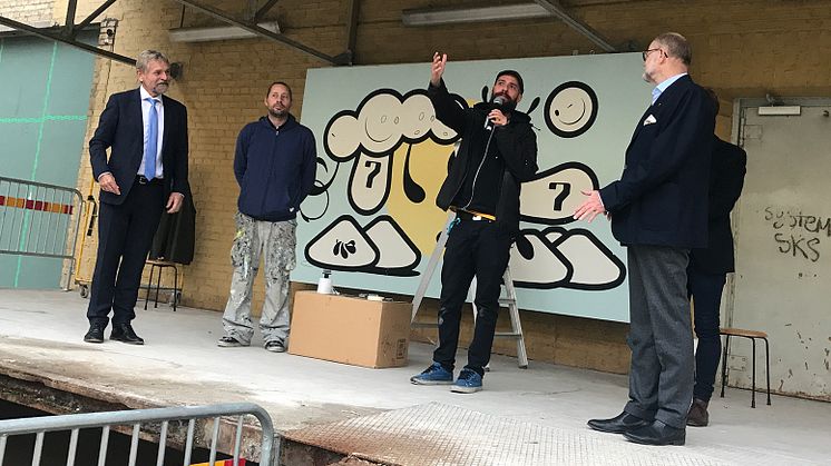 Högskolans rektor Björn Brorström (till vänster) blir glatt överraskad av presenten från konstnärerna London Police (mitten) som räcktes över av Per-Olof Höög, Kommunfullmäktiges ordförande i Borås Stad (till höger). 