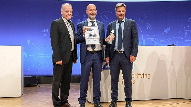 Bundeswirtschaftsminister Robert Habeck (rechts) und ZVEI-Präsident Dr. Gunther Kegel (links) übergeben Daniel Hager, CEO der Hager Group des Electrifying Ideas Award des ZVEI.