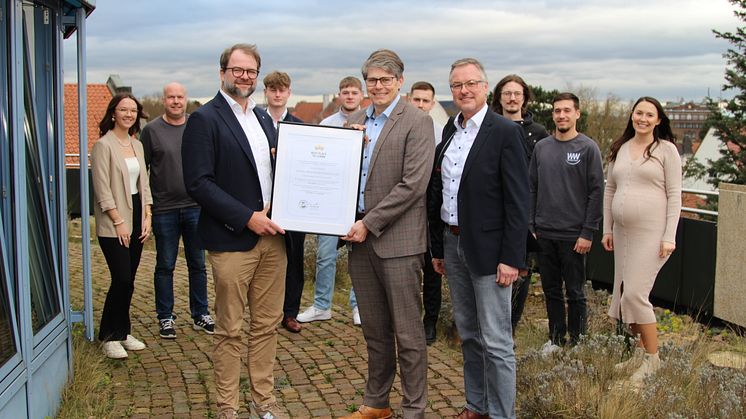 Niels Köstring übergibt die Urkunde an Personalleiter Guido Merzbach und Burkhard Thiele (vorn v. l.). Große Freude bei Azubis, Ausbilder und Ausbildungsbeauftragten