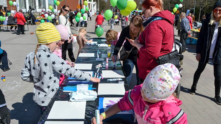 Tiina Herttua koostaa seinänkokoisen taideteoksen työpajoissa maalatuista laatoista.