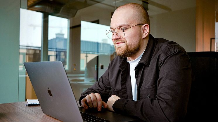 Leende man framför dator på kontor