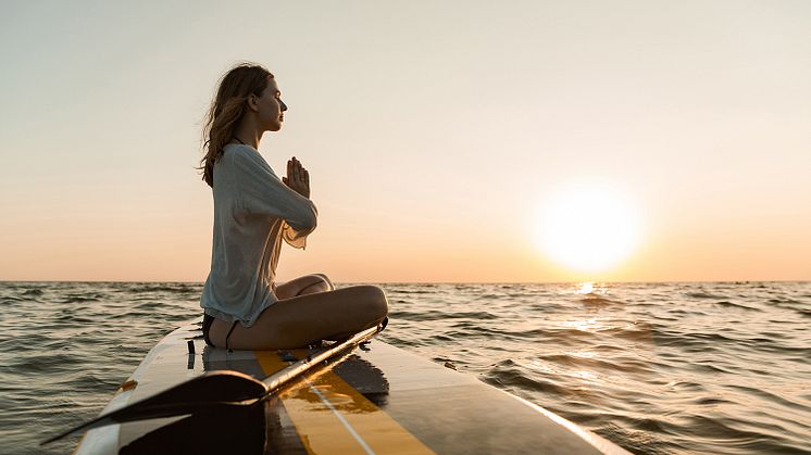 Junge Frau entschleunigt auf Paddleboard