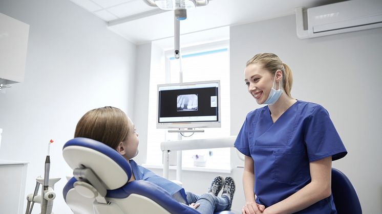 Leende tandvårdspersonal med ung patient på klinik.