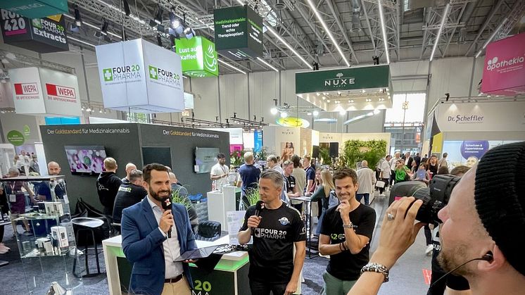 Thomas Schatton (schwarzes Trikot, Mikro) und Torsten Greif (schwarzes Shirt) beim Interview mit dem Messe-TV der expopharm.