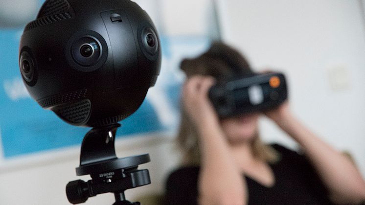 Syntolkning: VR-kamera i förgrunden och en person med VR-glasögon i bakgrunden. Foto Mikael Ström